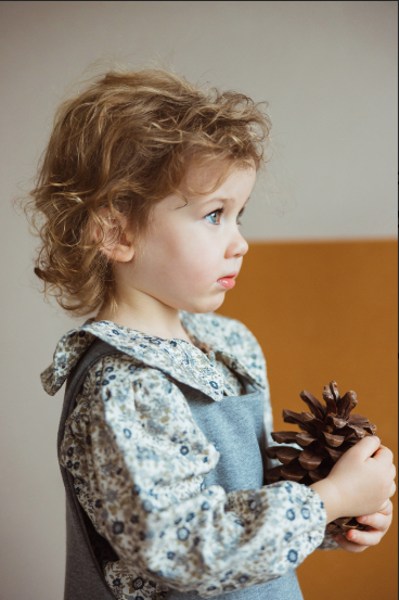 Child wearing floral print shirt under a dress.