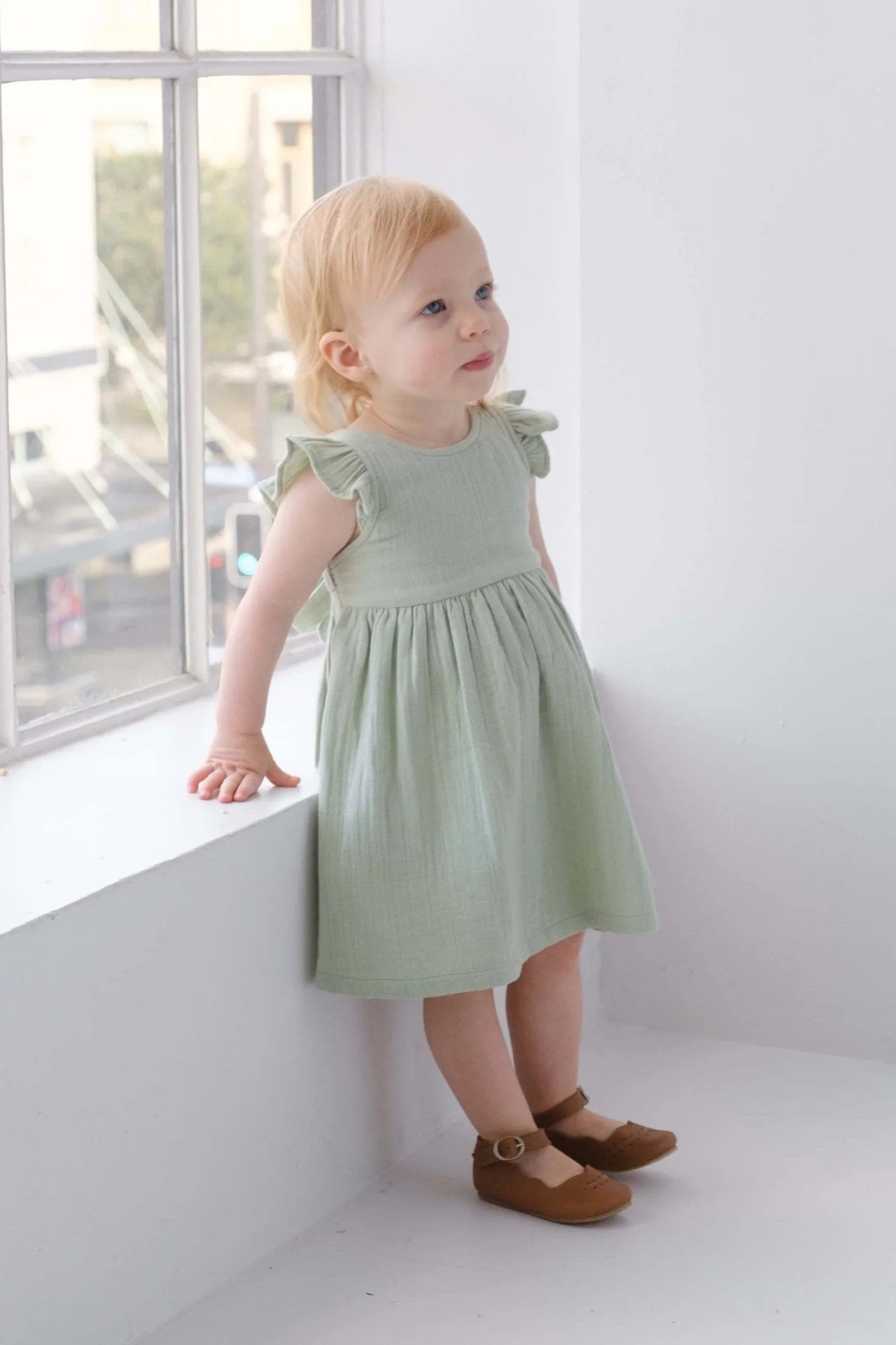 child wearing sage green ruffle dress with bow tie at back