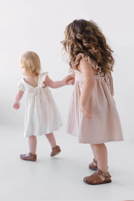 toddler wearing ruffle white dress back view with bow tie detail