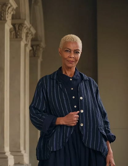 Woman wearing a navy blue linen striped jacket and dress in a classic architectural setting