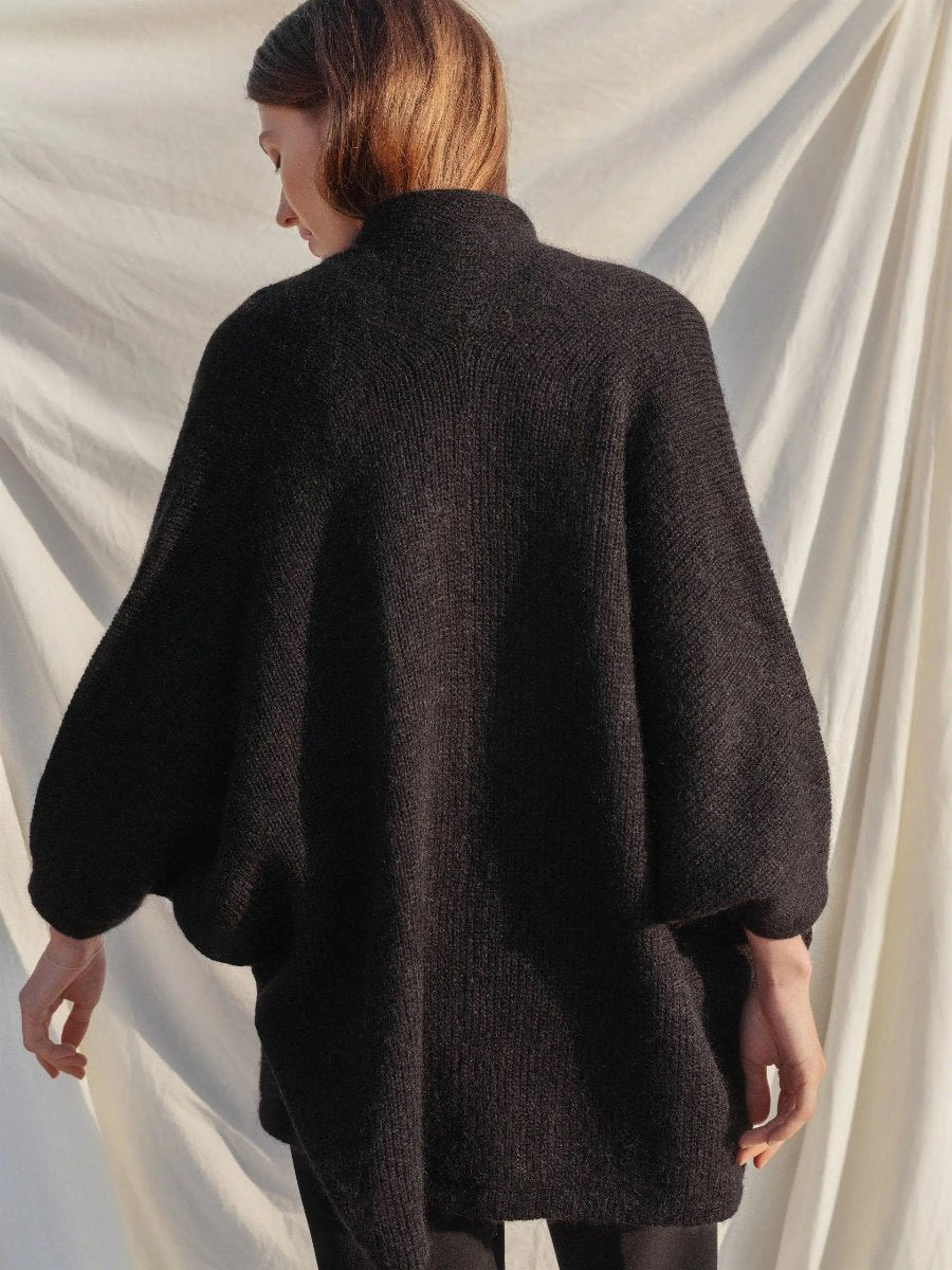 Woman wearing black poncho back view