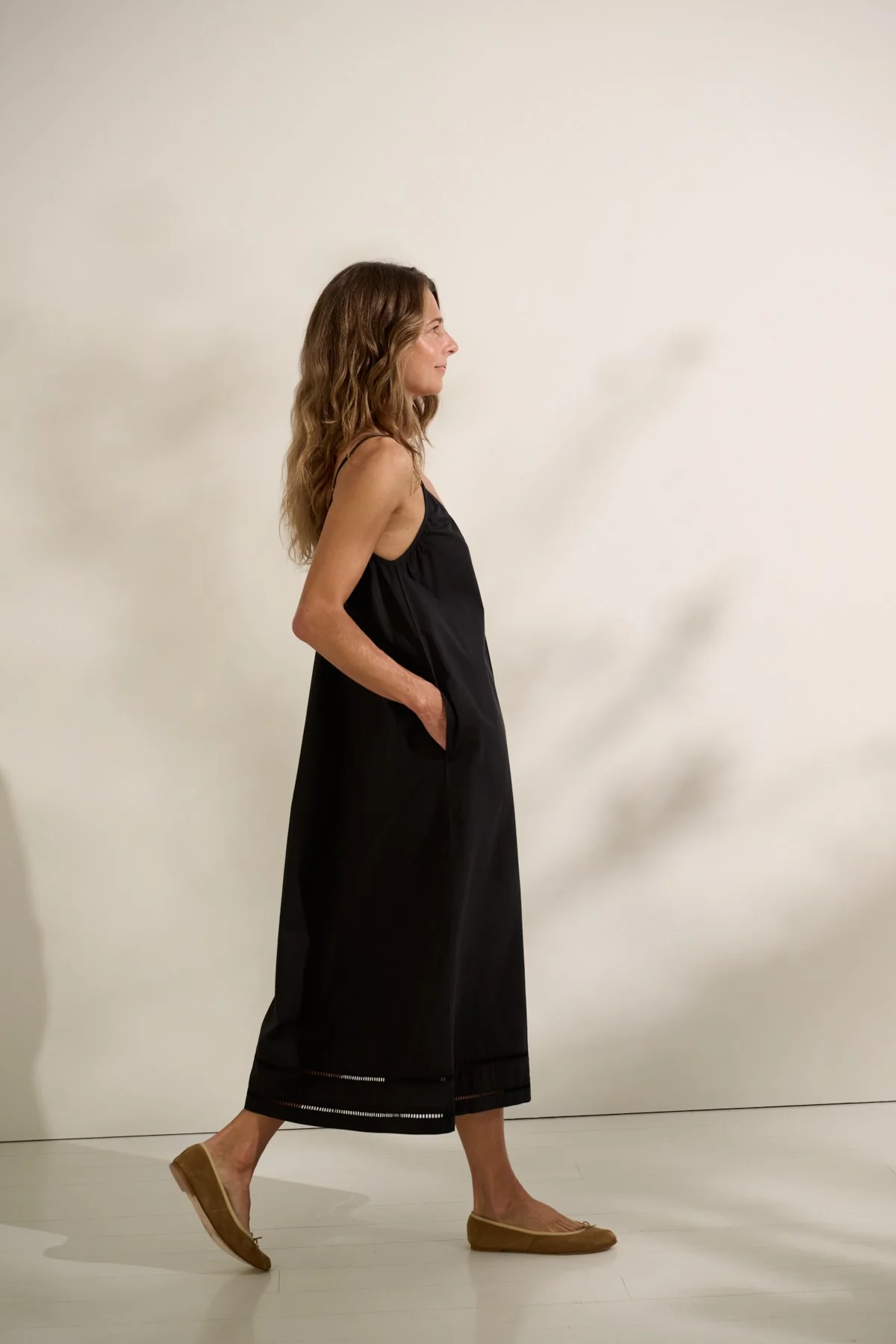 Woman wearing black popllin sundress side view.