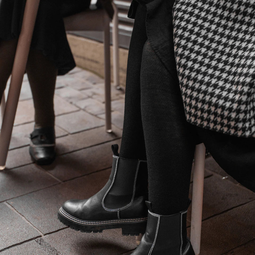 Woman wearing black wool textured tights and boots.