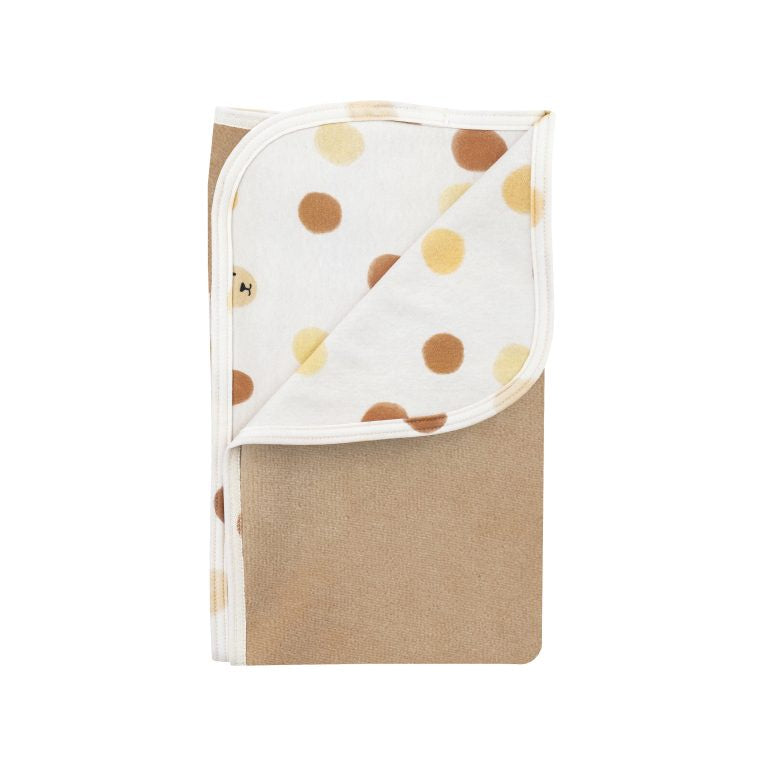 Beige linen blanket with white and brown polka dot pattern, folded neatly.
