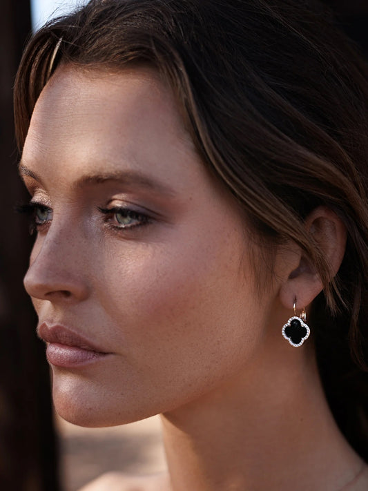 Model wearing rose gold earrings with black paua and zircons