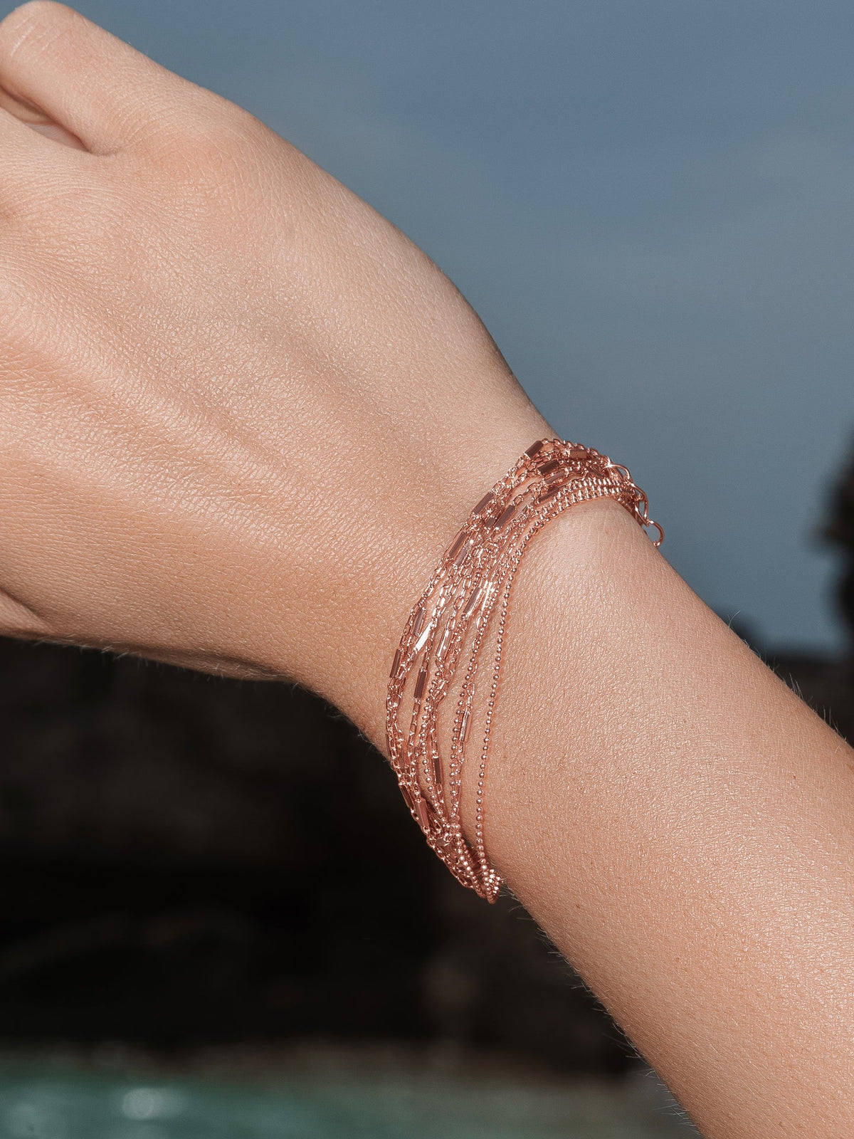 Woman wearing fine chains rose gold bracelet.