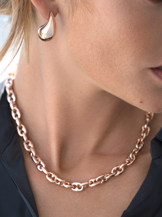 Woman wearing a chunky chain necklace in rose gold.