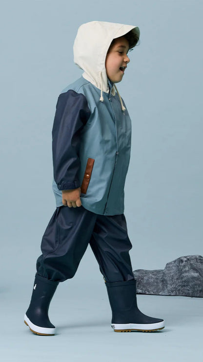 Boy walking in earth and sky colour play jacket with hood up.