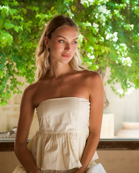 Woman wearing strapless cotton peplum top with shirred back detail.