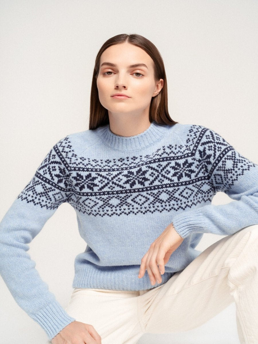 Woman wearing blue nordic sweater sitting down