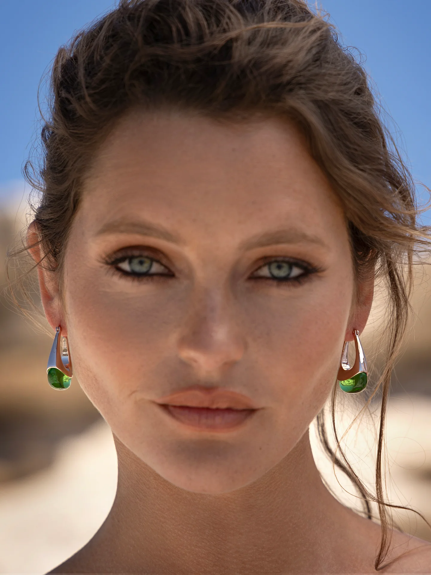 woman wearing rose gold loop earring with green glass finish.
