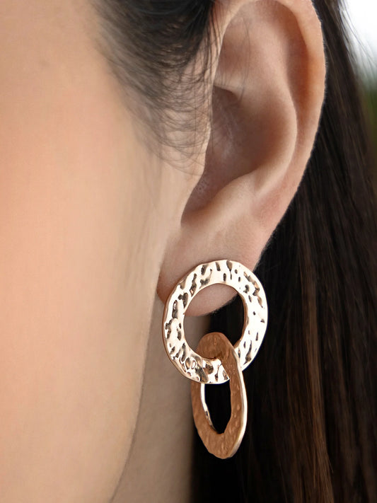 Close-up of a woman's ear wearing gold hammered statement earrings with interlocking circles