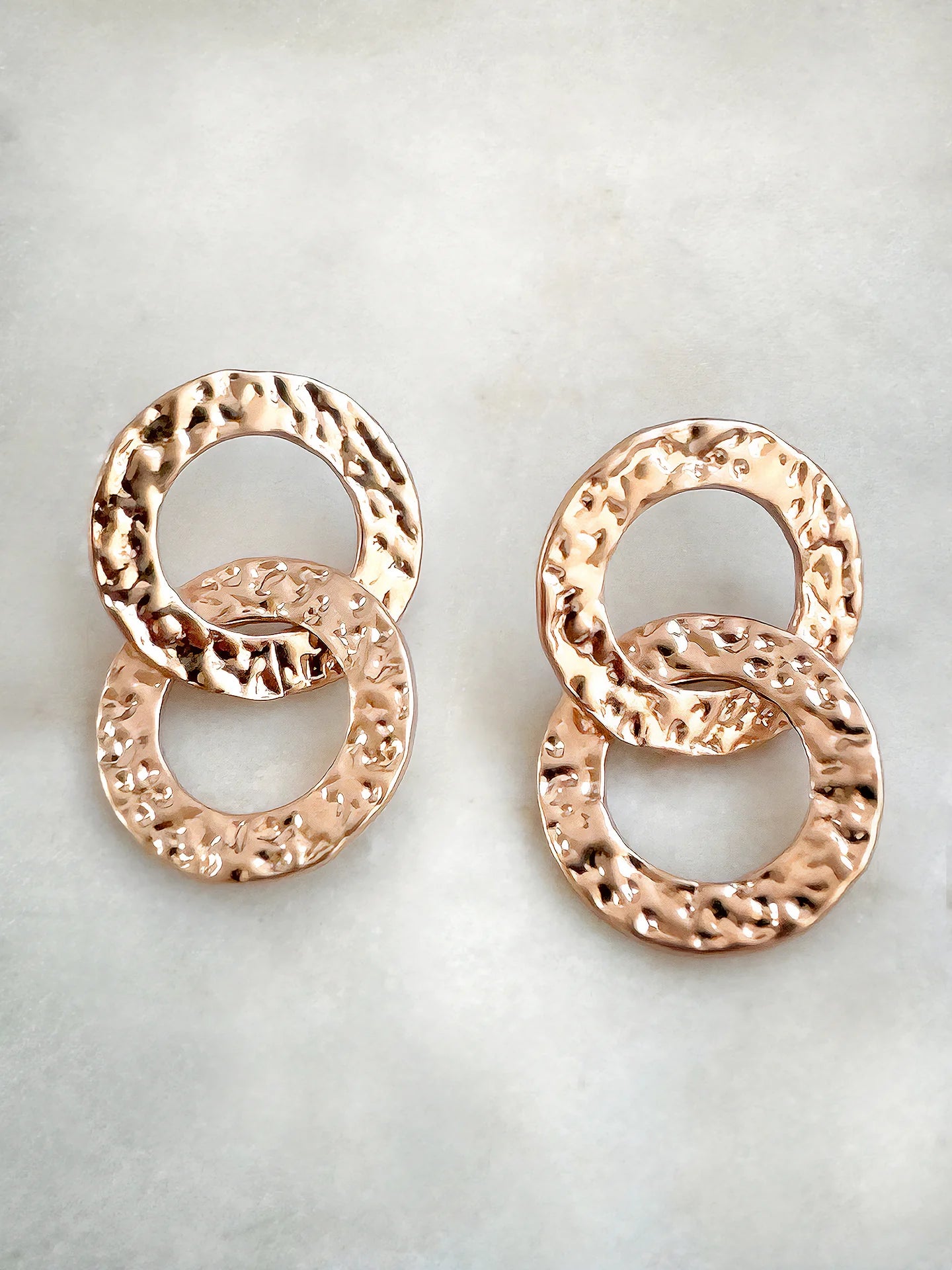 Hammered gold-tone double circle earrings on a white background