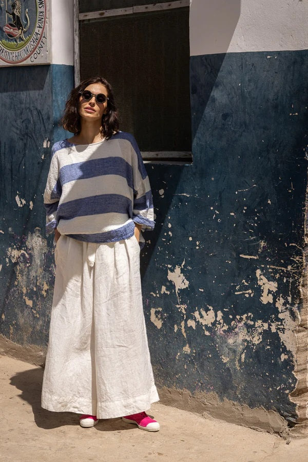 Woman wearing wide leg linen pants in white with tie waist.