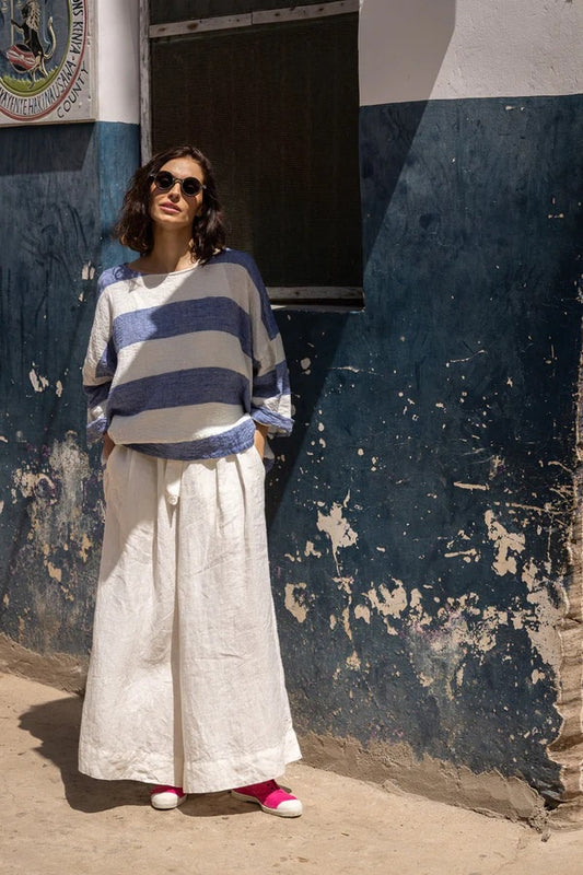 Woman wearing wide leg linen pants in white with tie waist.