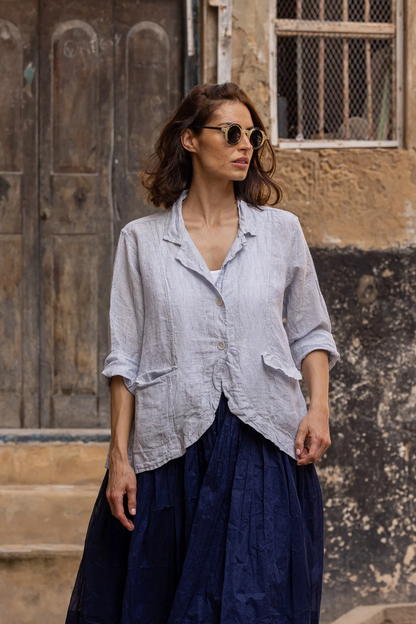 Woman wearing a light linen striped jacket with pockets and navy skirt outdoors
