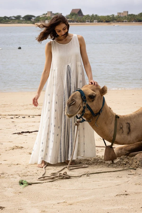 Woman wearing A-line sleeveless linen dress with inverted front and back pleat in linen print fabric.