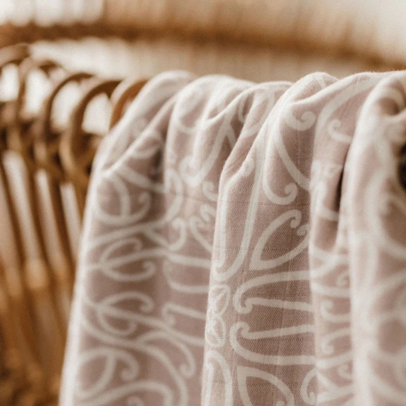Beige linen fabric with white koru-inspired pattern draped over a rattan chair.