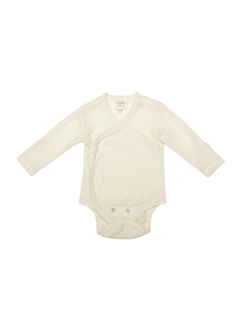 Cream merino wool baby bodysuit with long sleeves and snap buttons, laid flat on white background