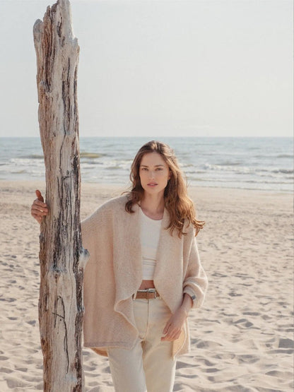 woman standing on beach wearing cream wrap