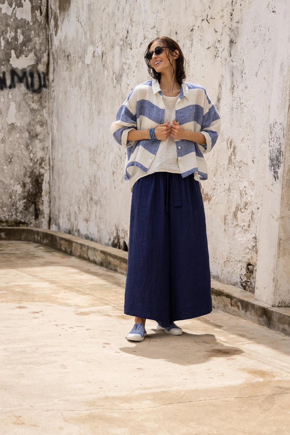Woman wearing a blue striped linen shirt and wide leg navy linen pants outdoors