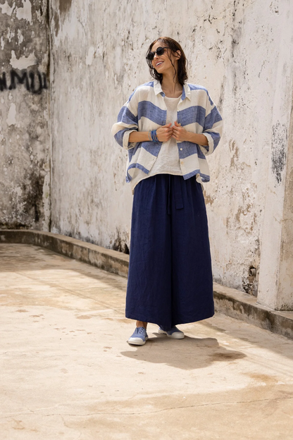 Woman wearing a blue striped linen shirt and wide leg navy linen pants outdoors