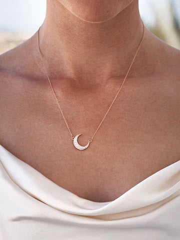 Woman wearing a delicate moon necklace in rose gold plate.