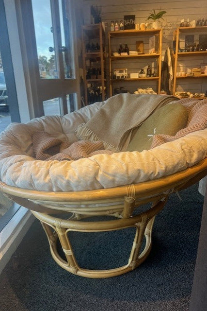 Papasan chair with cozy linen and wool throws in a boutique shop setting by the window