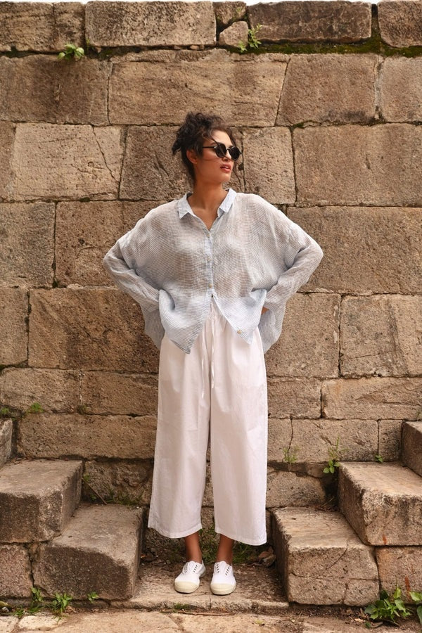 Woman wearing wide leg white cotton twill pant with elastic smocked waist.
