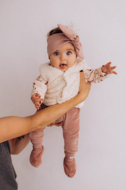Baby wearing velour pants in soft rosewood colour.