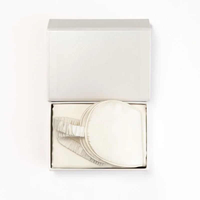 Silk white sleep mask with elastic strap in gift box on white background
