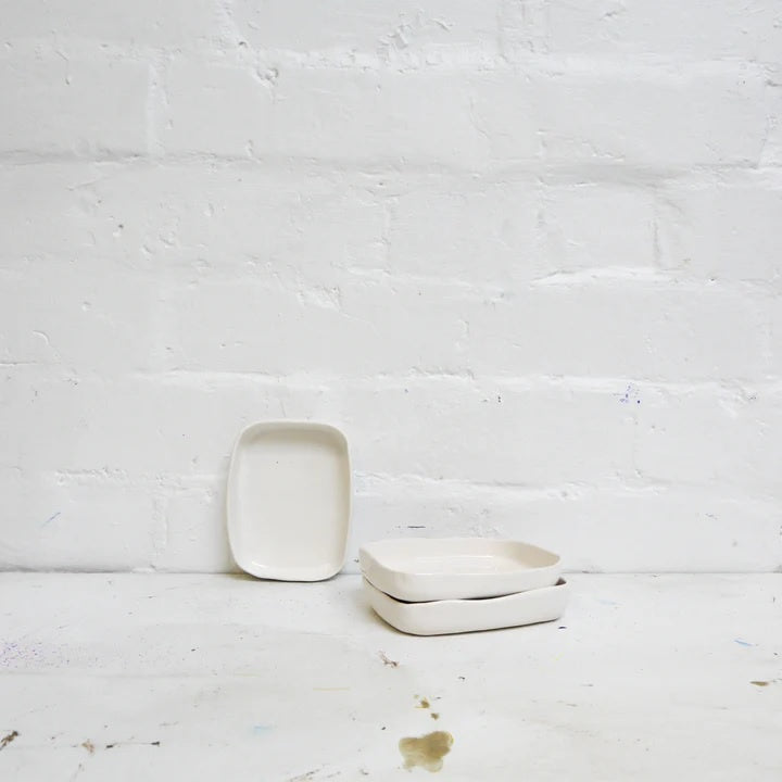 Minimalist ceramic soap dishes stacked on a white background, rectangular shape.