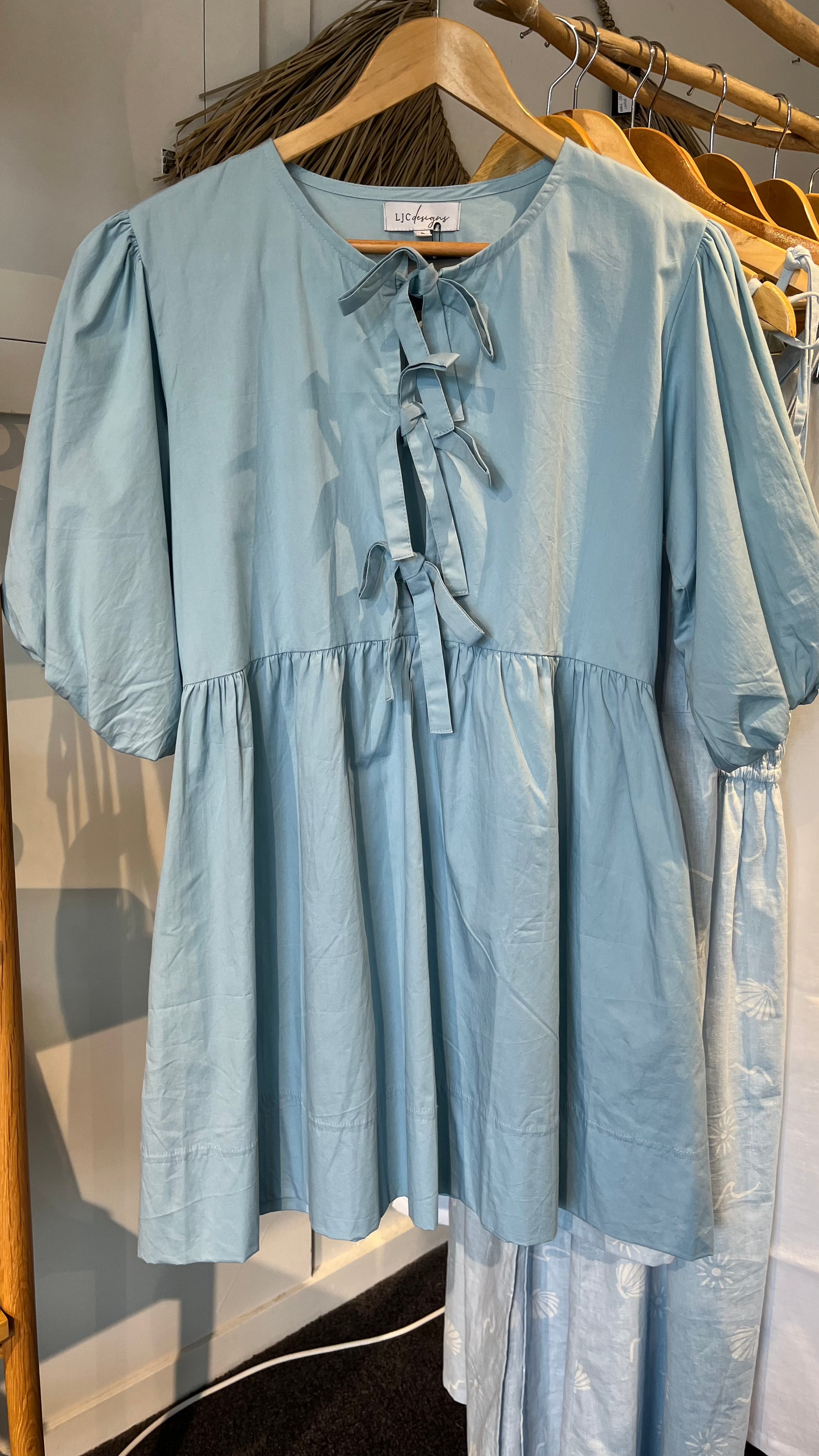 Sky Blue Poplin dress with tie front details on hanger