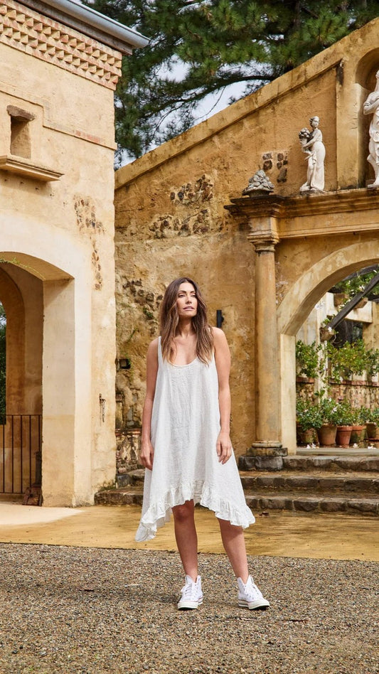 Woman wearing cream coloured slip dress with ruffle at bottom