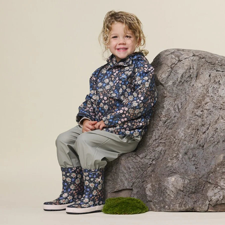 Child wearing waterproof play jacket in winter floral design.