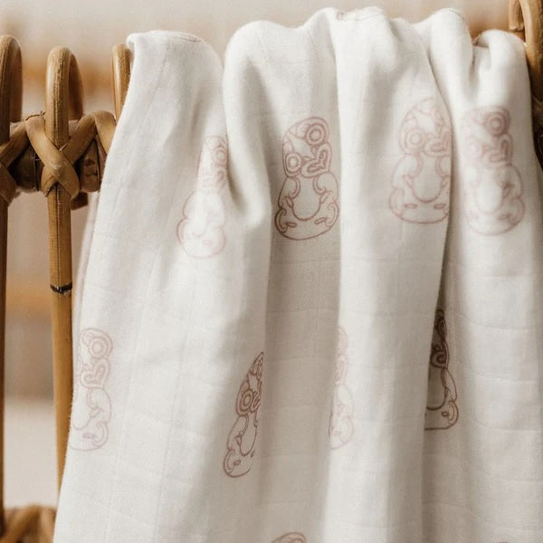 White linen wrap with light mauve pattern, draped on wooden rack