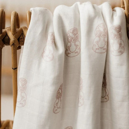 White linen wrap with light mauve pattern, draped on wooden rack