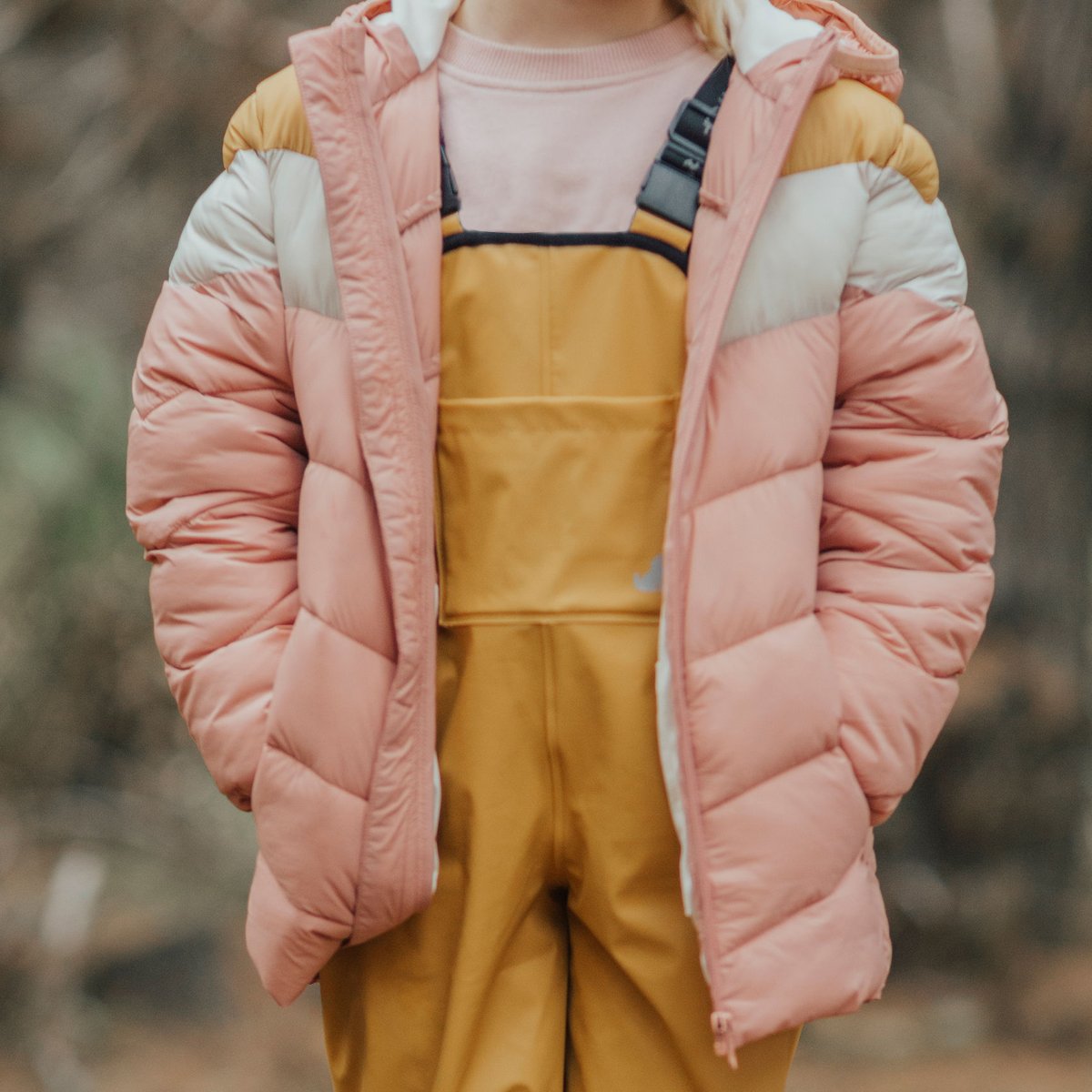 child wearing yellow overalls and pink jacket