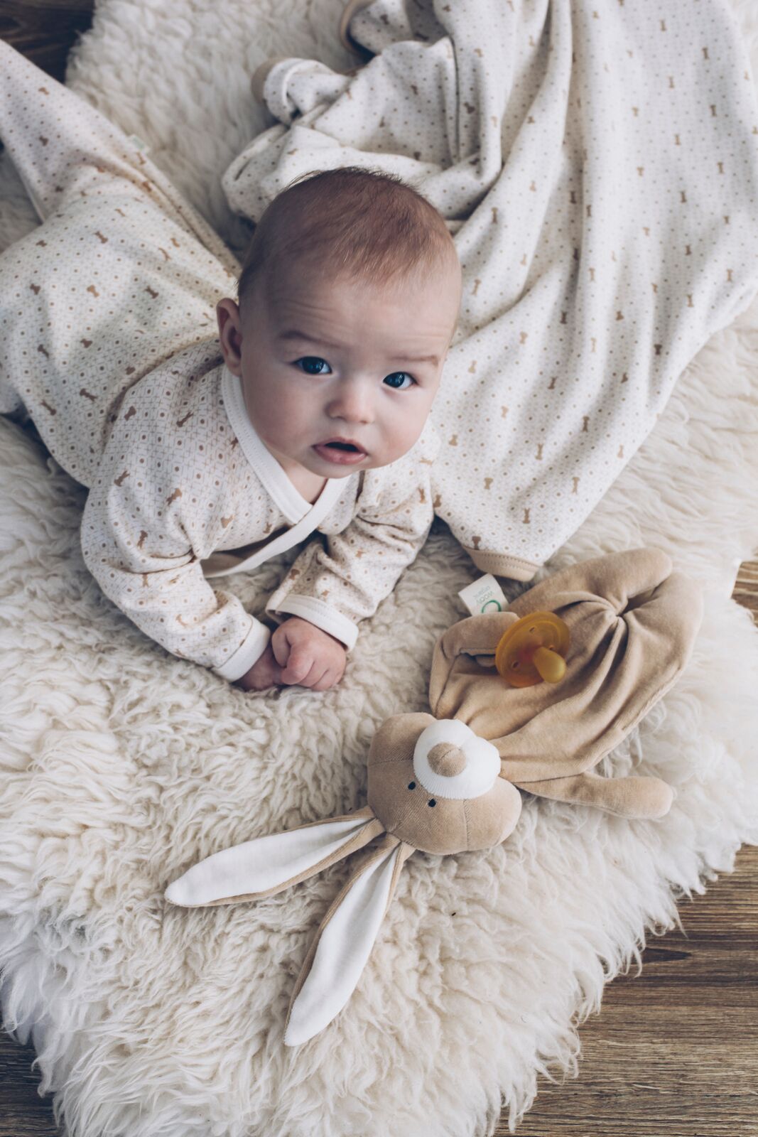 Baby with comforter bunny laying on bed
