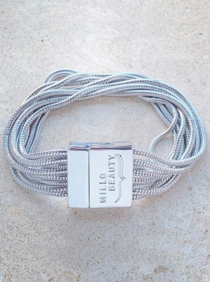 Silver snake chain bracelet with multiple strands and engraved clasp on neutral background