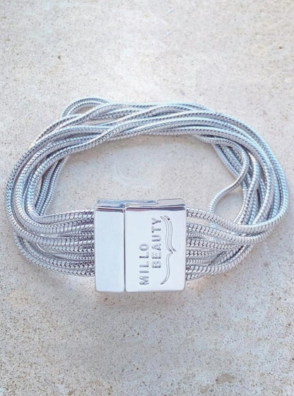 Silver snake chain bracelet with multiple strands and engraved clasp on neutral background