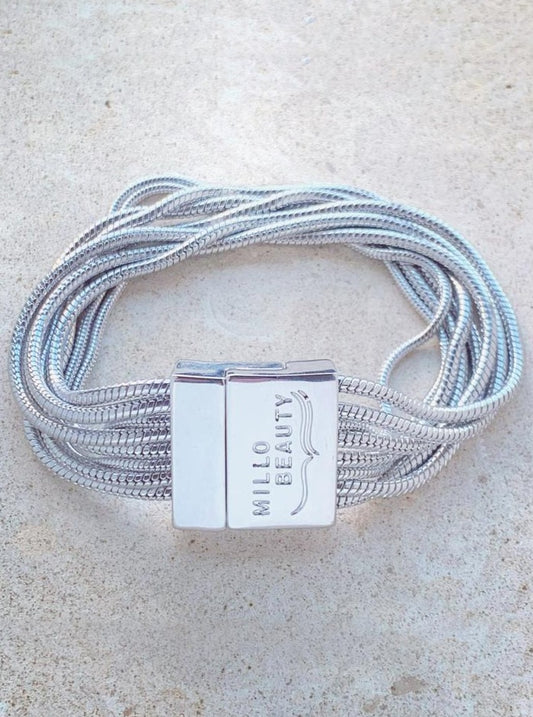 Silver snake chain bracelet with multiple strands and engraved clasp on neutral background