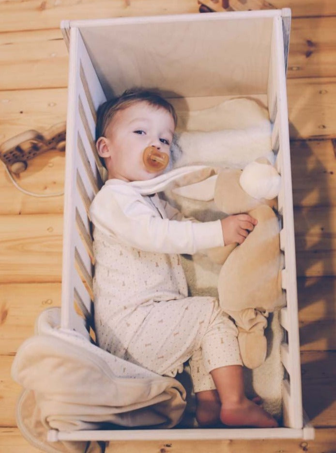 Baby in cot wearing organic cotton sleepsuit