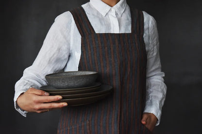 lady in white shirt and apron holding dishes