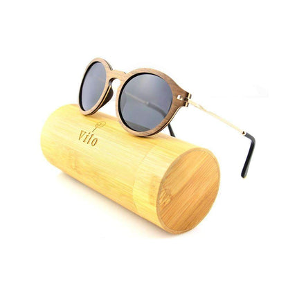 Round wooden sunglasses with dark lenses resting on a bamboo case