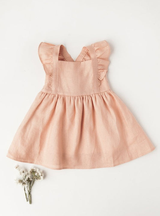 Blush pink linen dress with ruffle straps, laid flat on white background with dried flowers.